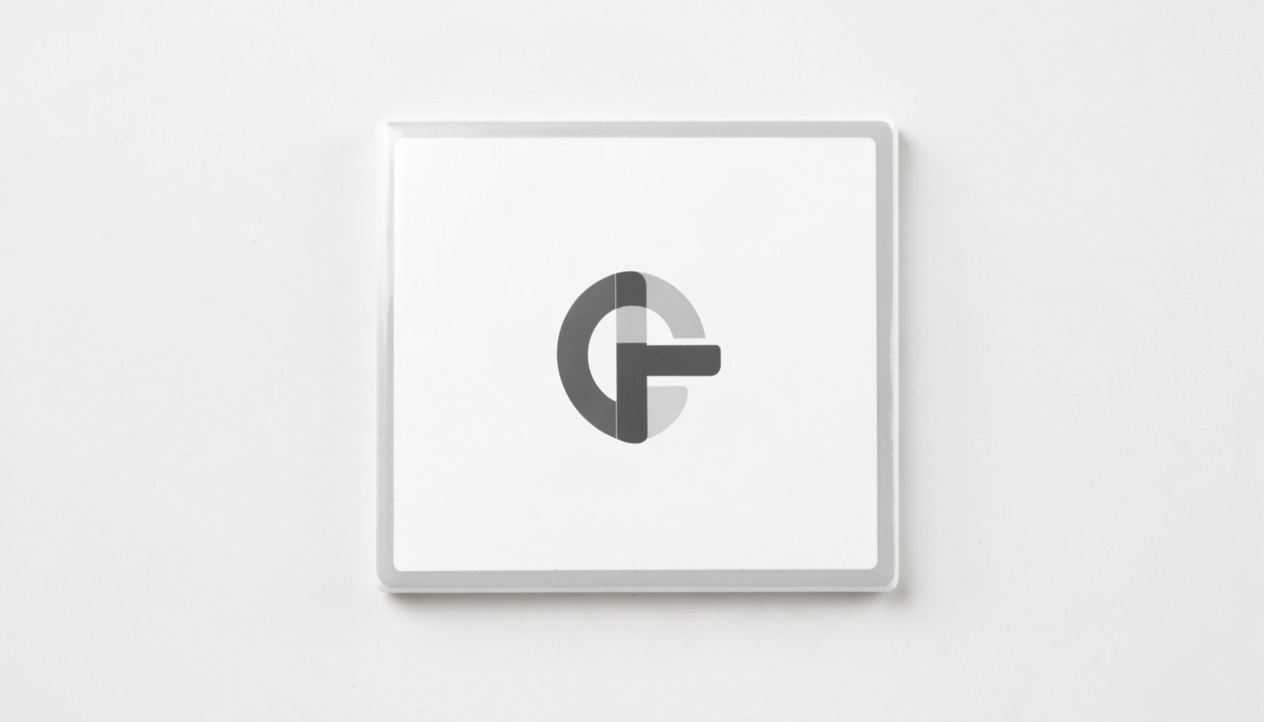 A square logo tile with a white background and a thin light-grey border, featuring a minimalist dark-grey symbol.