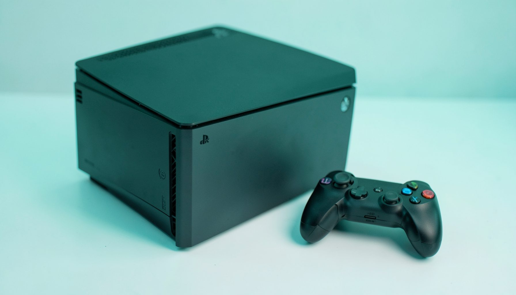 A PlayStation 3 console with a controller beside it, photographed on a white surface with soft teal-tinted lighting.